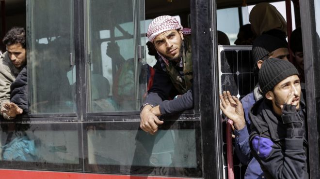 Сирийские гражданские лица и повстанцы, эвакуированные из Харасты в Восточной Гуте, смотрят в окна в автобусе, который доставляет их в провинцию Идлиб (25 марта 2018 года)
