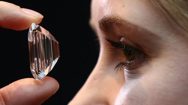 Женщина смотрит на бриллиант в 100 карат