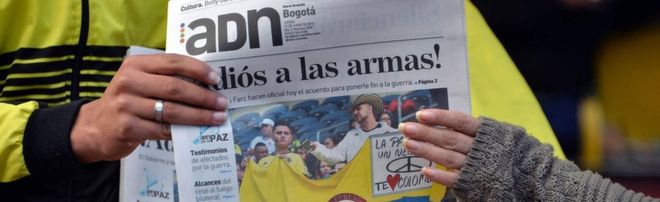 Колумбийцы читают газеты с заголовками о соглашении о прекращении огня между правительством и Фарком в Боготе 23 июня