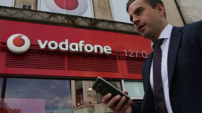 Мужчина пользуется смартфоном, проходя мимо магазина Vodafone в центре Лондона 16 мая 2017 года.