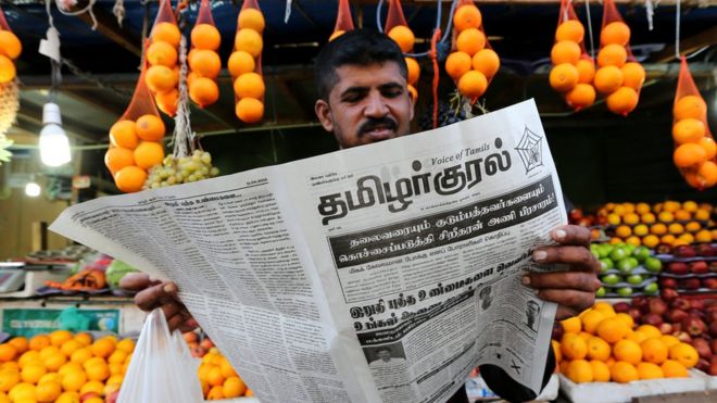 Man reading Tamil language paper