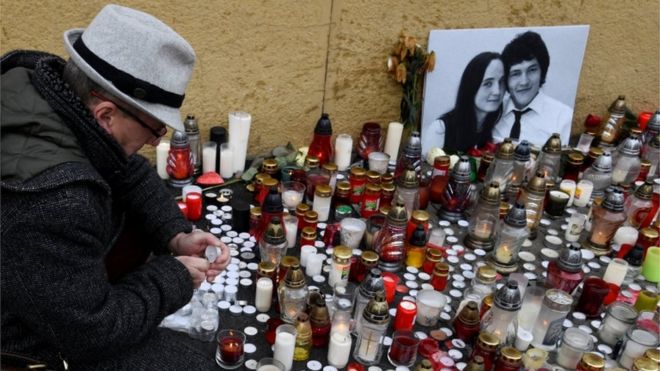Мужчина зажигает свечу за дань уважения убитому словацкому журналисту-расследователю Яну Кучаку на Словацкой национальной площади восстания в Братиславе