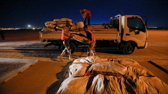 Three men load a truck with aid for Syria
