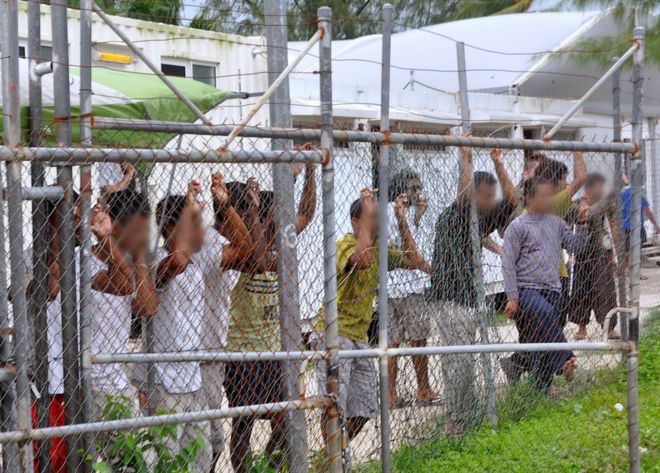 Просители убежища просматривают забор в центре заключения на острове Манус в Папуа-Новой Гвинее 21 марта 2014 года.