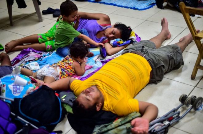 Мужчина, женщина и двое маленьких детей отдыхают во временном приюте в Сьюдад-Идальго, Мексика