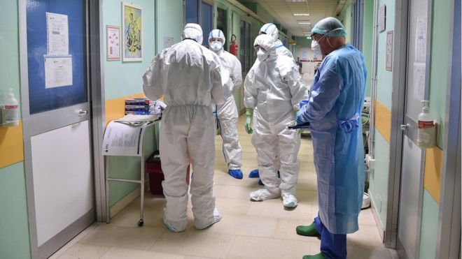 Медицинские работники в защитных костюмах и медицинских масках работают в изолированной зоне больницы Амедео ди Савойя в Турине, северная Италия