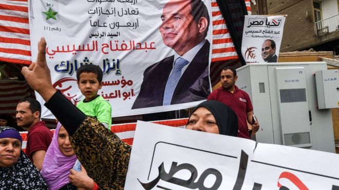 Сторонник Абдул Фаттах аль-Сиси делает жест победы возле избирательного участка в Гизе, Каир (28 марта 2018 года)