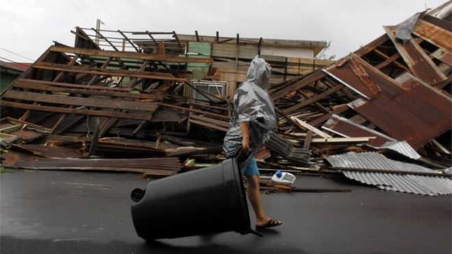 Mulher caminha em frente a uma construção derrubada pelo furacão Maria em Fajardo.
