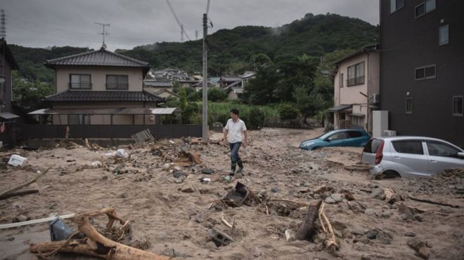 Человек проходит мимо опустошенной улицы во время наводнения в Саке