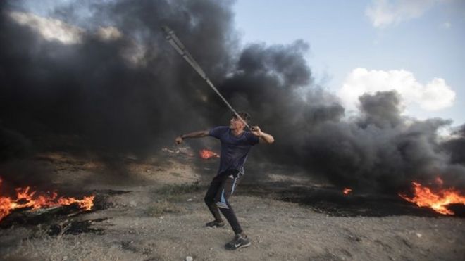 Палестинский протестующий принимает участие в столкновениях с израильскими войсками у границы с Израилем на востоке города Газа 20 июля 2018 года.