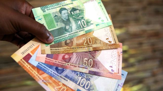 Мужчина держит банкноты южноафриканского ранда