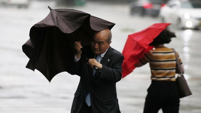 Мужчина борется с зонтиком при приближении тайфуна Линглинг в Сеуле, Южная Корея, 7 сентября 2019 г.