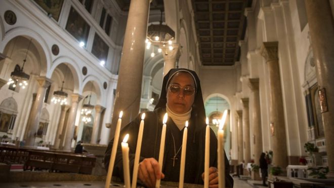 A nun lights a candle as Catholics attend the Christmas eve mass at Saint Joseph Catholic Church in Cairo,