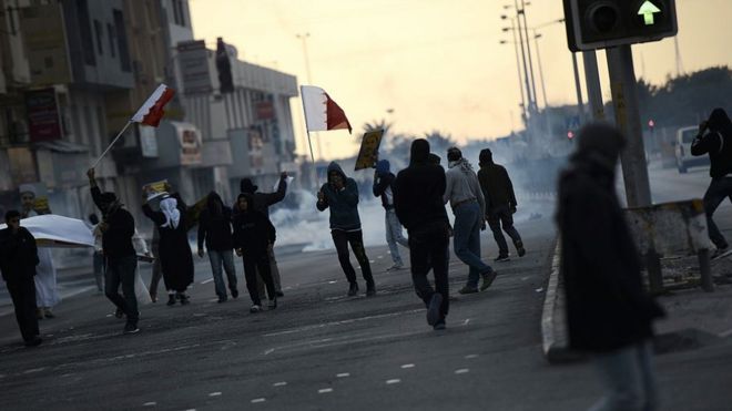 Протестующие в Бахрейне пытаются скрыться от слезоточивого газа, выпущенного полицией во время столкновений на митинге в Ситре 29 января 2016 года