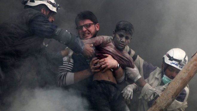 Мужчины спасают мальчика из-под обломков разрушенного здания после сообщения о правительственном авиационном ударе в удерживаемом повстанцами районе Шаар в Алеппо, Сирия (6 апреля 2014 года)