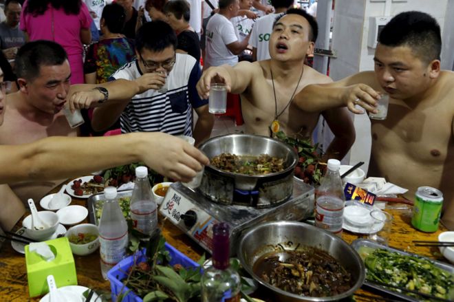 Мужчины едят собаку на Юлинском фестивале собачьего мяса