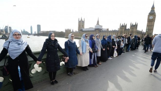 Группа женщин, некоторые со своими дочерьми, связывают руки на Вестминстерском мосту