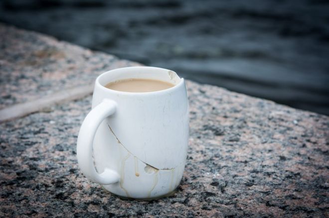 A cracked coffee cup next to the river