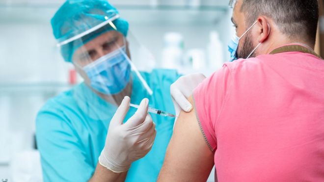 Un médico inyecta a un voluntario con una vacuna