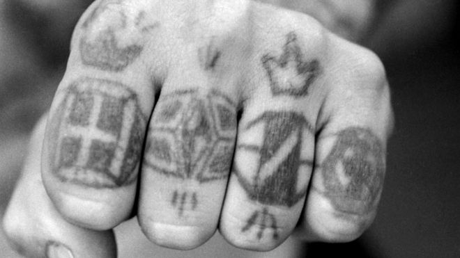 Кулак с татуировками на пальцах