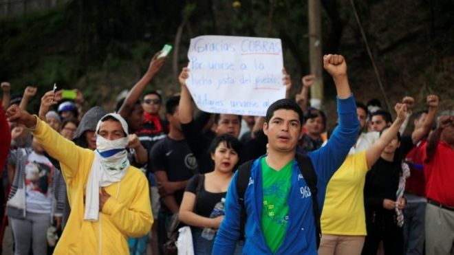 Люди поддерживают гондурасскую полицию во время забастовки, требуя повышения заработной платы и отдыха после дополнительных рабочих часов из-за протестов, вызванных задержкой в ??подсчете голосов на всеобщих выборах, в их штаб-квартире в Тегусигальпе, Гондурас, 4 декабря 2017 г.