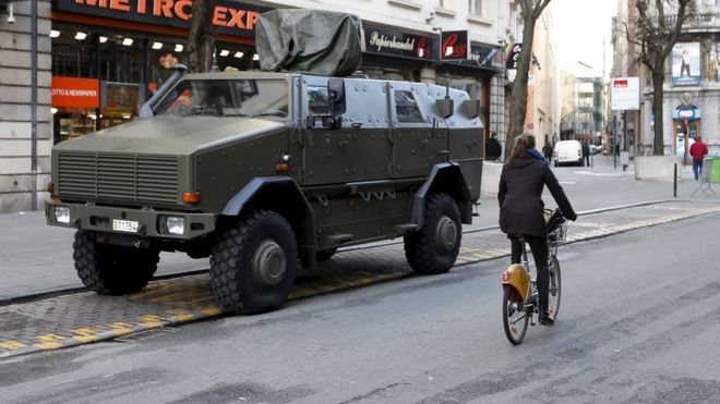 Велосипедист проезжает мимо военной бронированной машины в центре Брюсселя, 31 декабря 2015 г.