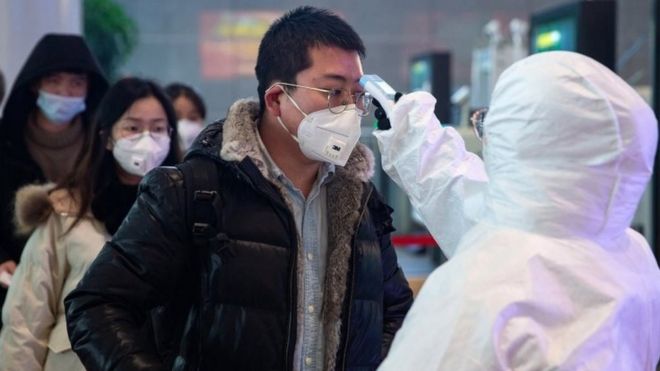 Profissional de saúde faz medição de temperatura em cidadão na China