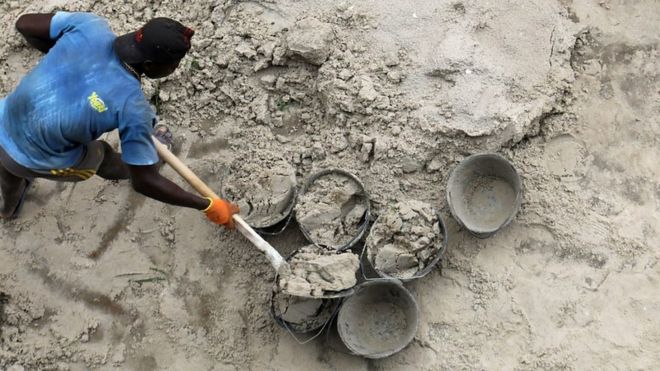 Un homme qui ramasse du sable