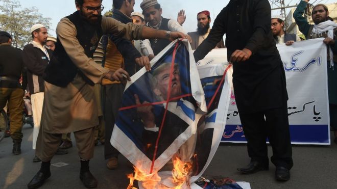 Pakistani demonstrators burn images of US President Donald Trump and the US flag during a protest against US aid cuts in Lahore on January 5, 2018.