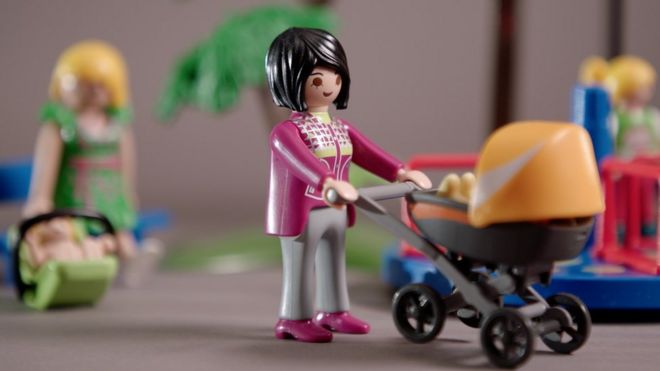 Boneca carregando carrinho de bebê