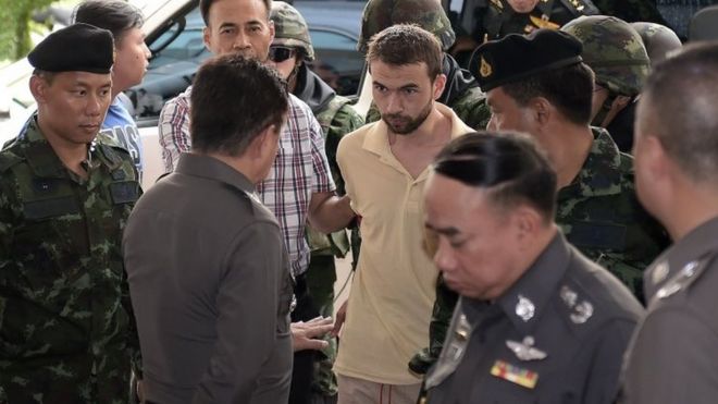 Мужчина, которого идентифицируют как Адема Карадака (в центре), подозреваемого в совершении иностранного преступления во время бомбежки святилища в Эраване 17 августа, сопровождается солдатами, когда он прибывает для допроса в полицию в столичном полицейском участке Бангкока (4 сентября 2015 года)