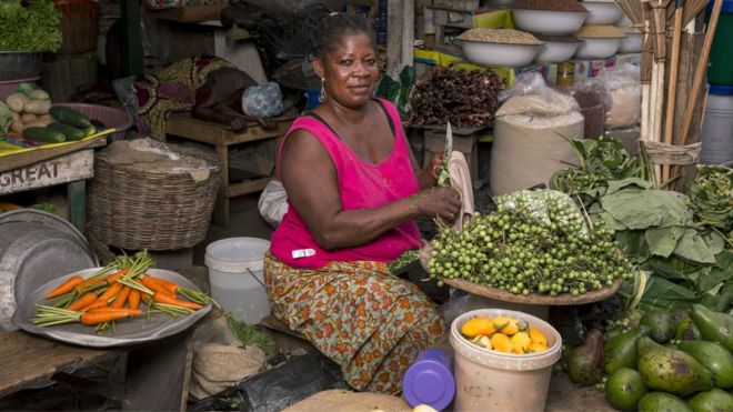 Неофициальная работница Виктория Оаоркорат ее овощной стенд на круглом рынке 13 августа 2015 года в Аккре, Гана