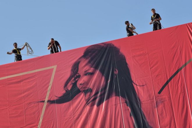 موظفون يضعون الملصق الجداري الخاص بمهرجان كان بفرنسا يوم 15 مايو/أيار 2017.