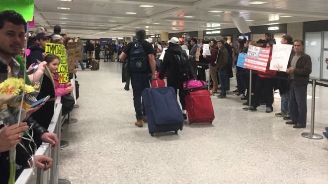 Родственники и сторонники ждали, чтобы поприветствовать прибывающих, которые были задержаны в международном аэропорту Даллеса в Вирджинии. Али, Хаджер и их сыновья, законные жители США, наконец-то добираются до зала прибытия. Али, Хаджер и их сыновья