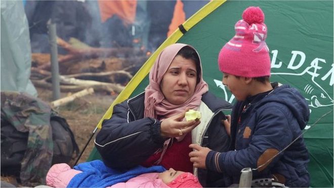 Image shows migrants eating at the camp at the Belarus-Polish border