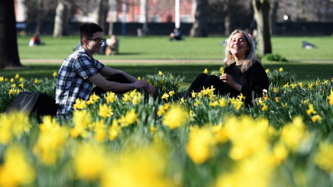 Два человека сидят среди нарциссов в парке Святого Джеймса в Лондоне во вторник