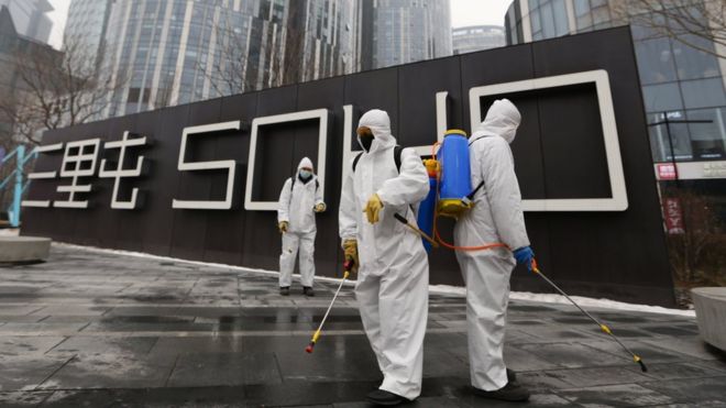 Workers wearing protective suits disinfect a commercial complex in Beijing following an outbreak of the coronavirus