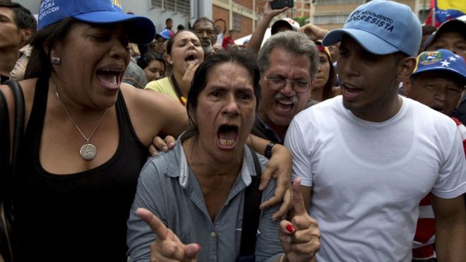 Женщина, стоящая возле центра проверки для подтверждения своей подписи, злится, узнав, что она закрылась в назначенный час, не посещая тех, кто все еще ждет, в Каракасе, Венесуэла, пятница, 24 июня 2016 г.