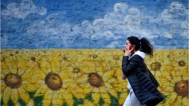 Жінка на тлі намальованих квітів у кольорах українського прапора