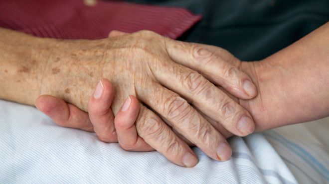 A senior holds hands with a younger person