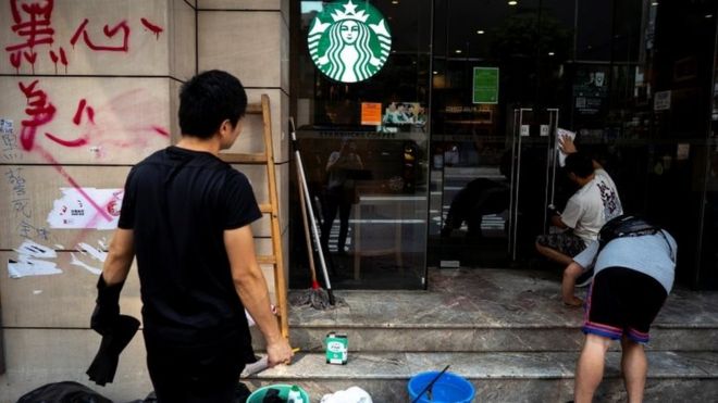 Рабочий чистит граффити в кофейне Starbucks в Гонконге 30 сентября