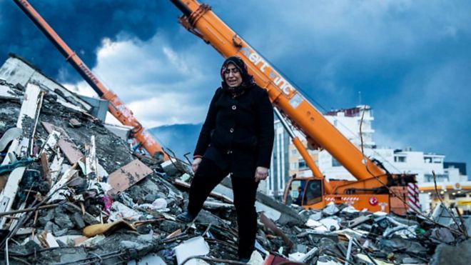 一名婦女站在建築坍塌廢墟上