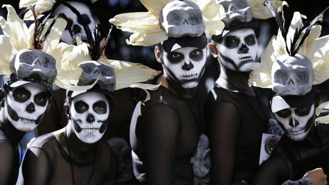 Hombres vestidos con trajes de esqueleto esperan el comienzo del desfile del Día de los Muertos en la avenida Reforma de Ciudad de México.