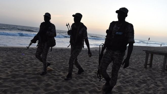 Ивуарийские солдаты идут по пляжу после того, как вооруженные вооруженные люди открыли огонь 13 марта 2016 года в отеле на пляжном курорте Кот-д'Ивуар в Гранд-Бассаме