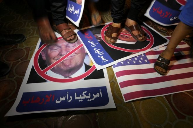 Палестинский демонстрант встает на плакат с изображением Дональда Трампа в Рафахе, в южной части сектора Газа, 22 мая