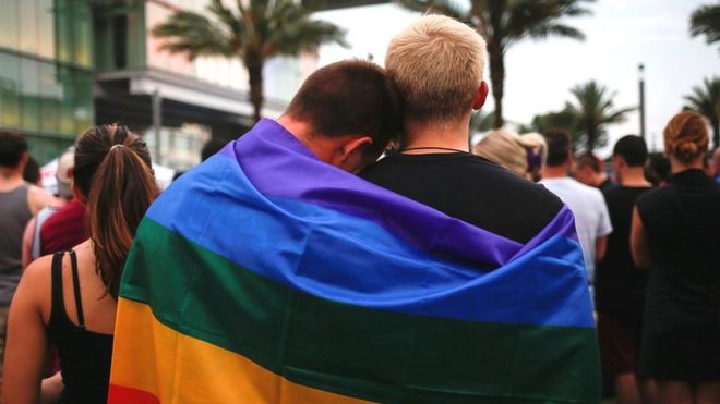 Dos hombres envueltos en una bandera del movimiento gay en Orlando, Florida