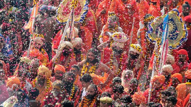 Индийские преданные поливают лепестки цветов индуистским святым во время религиозного шествия в район Сангама во время «королевского входа» на предстоящий фестиваль Кумбха-Мела в Аллахабаде 2 января 2019 года