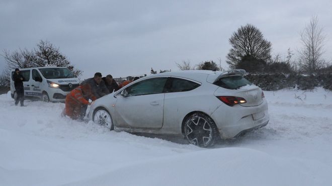 Мужчины толкают машину в снегу