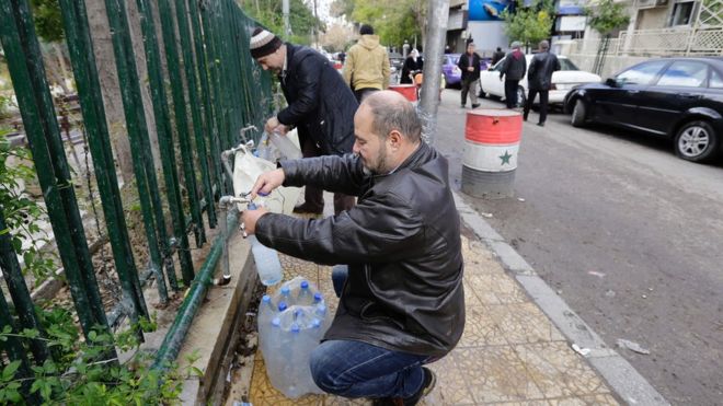 Residents of Damascus filling up water bottles in the streets during shortages
