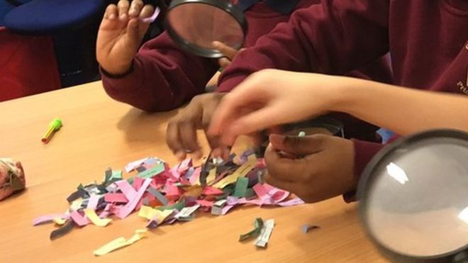 Children looking at small pieces of coloured paper